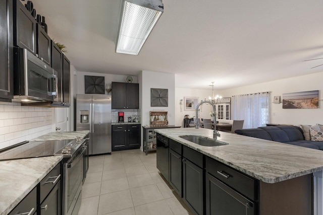 kitchen with a center island with sink, appliances with stainless steel finishes, backsplash, a chandelier, and light tile floors