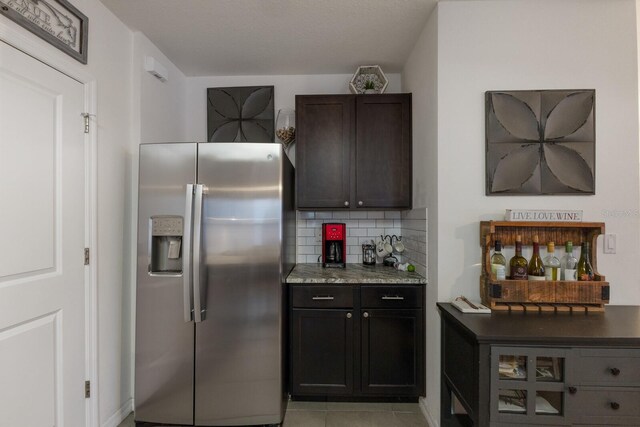 kitchen with dark brown cabinets, stainless steel fridge with ice dispenser, light tile floors, and tasteful backsplash