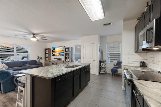 kitchen with dishwasher, backsplash, ceiling fan, range with electric stovetop, and a kitchen island with sink