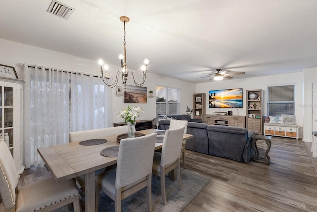 dining room with dark hardwood / wood-style floors and ceiling fan with notable chandelier