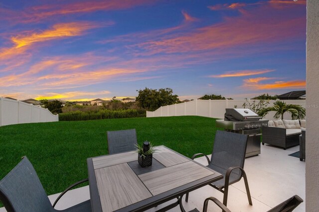 patio terrace at dusk featuring an outdoor living space, area for grilling, and a lawn