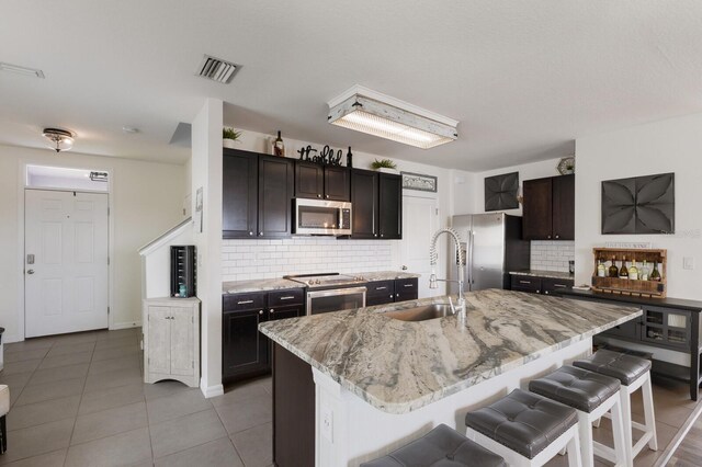 kitchen featuring sink, tasteful backsplash, a center island with sink, and stainless steel appliances