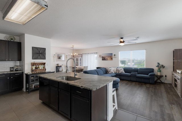 kitchen featuring ceiling fan with notable chandelier, a center island with sink, tasteful backsplash, a breakfast bar area, and sink