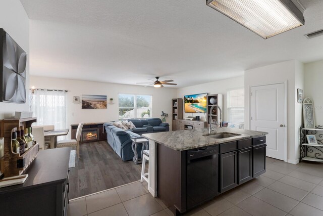 kitchen featuring ceiling fan, a center island with sink, dishwasher, tile floors, and sink