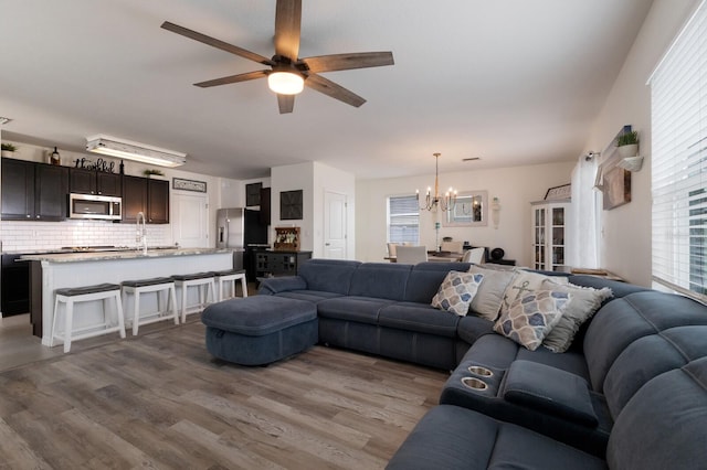 living room featuring plenty of natural light, wood-type flooring, and ceiling fan with notable chandelier