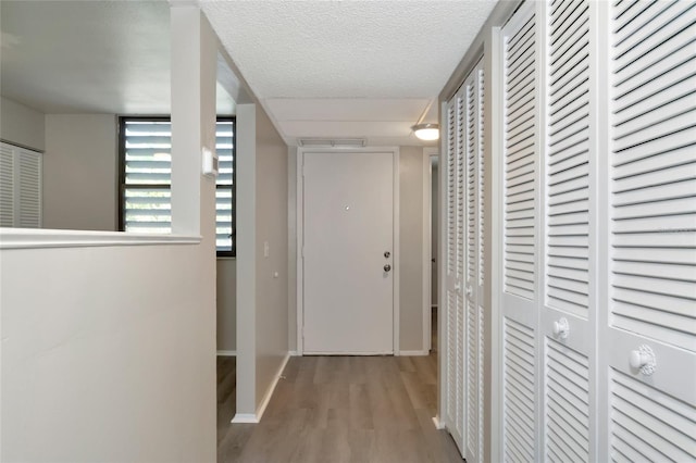 hall with a textured ceiling and light hardwood / wood-style floors