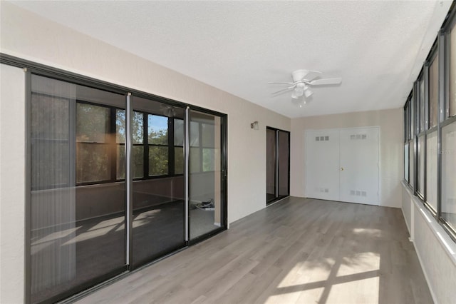 spare room featuring light wood-type flooring, a textured ceiling, and ceiling fan