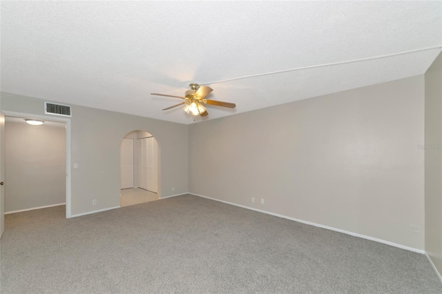 empty room featuring ceiling fan, light carpet, and a textured ceiling