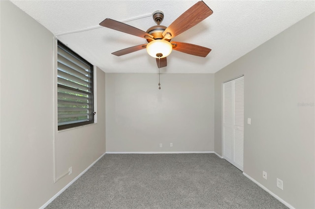 empty room with ceiling fan, carpet flooring, and a textured ceiling