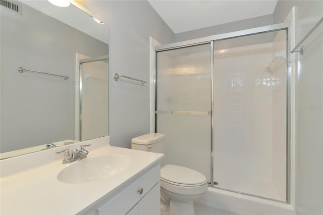 bathroom featuring toilet, a shower with door, and vanity