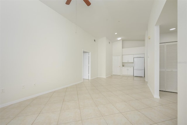 empty room with ceiling fan, light tile patterned flooring, and high vaulted ceiling