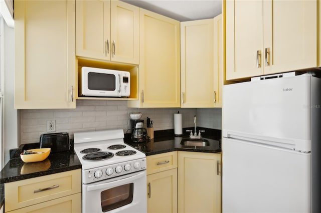 kitchen with dark stone countertops, sink, white appliances, and backsplash