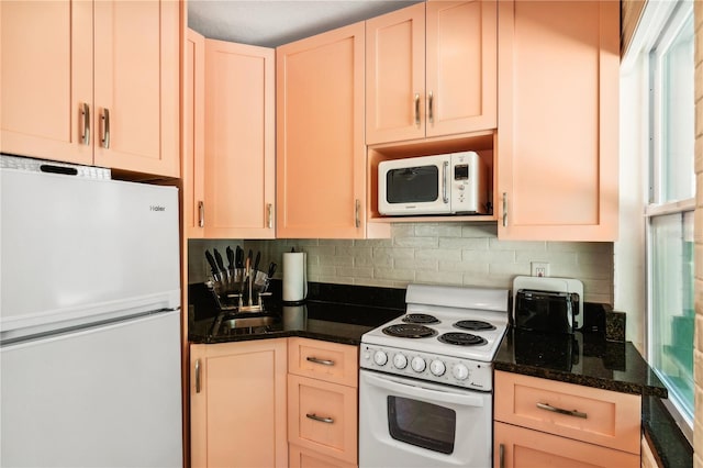 kitchen with decorative backsplash, light brown cabinetry, white appliances, and dark stone counters