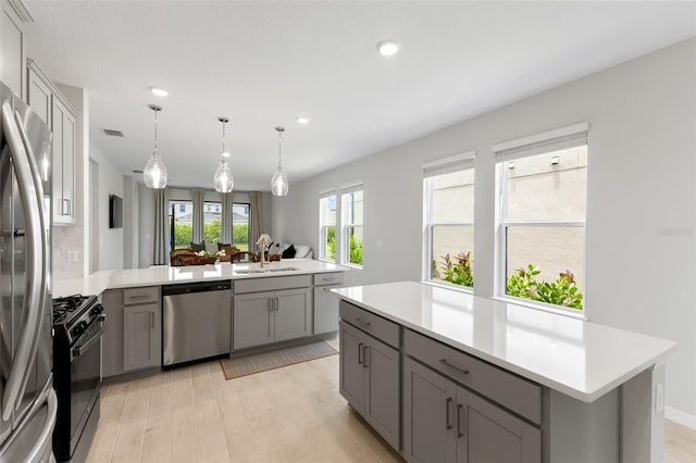 kitchen with sink, gray cabinets, appliances with stainless steel finishes, a kitchen island, and kitchen peninsula