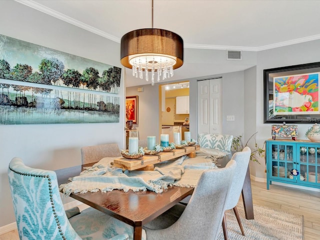 dining area featuring light hardwood / wood-style floors, an inviting chandelier, and crown molding