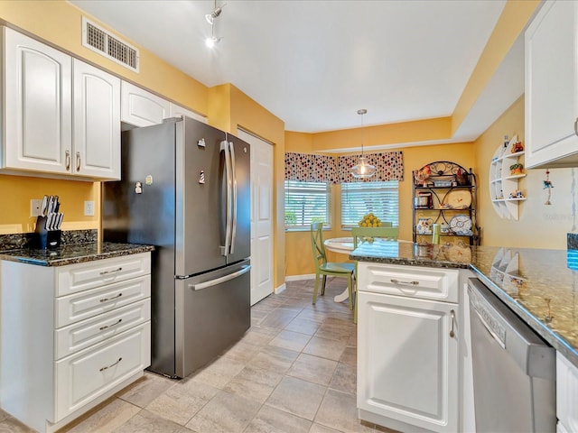 kitchen with kitchen peninsula, stainless steel appliances, dark stone countertops, white cabinets, and hanging light fixtures