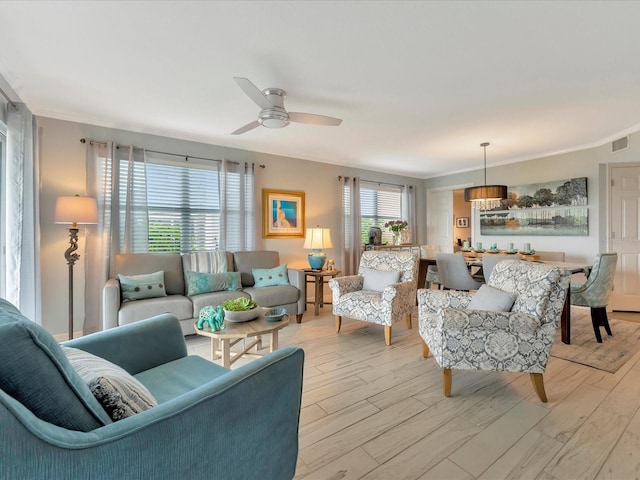 living room with ceiling fan, ornamental molding, and light hardwood / wood-style flooring