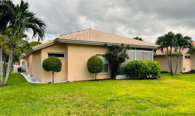 view of property exterior featuring a tiled roof, a lawn, and stucco siding