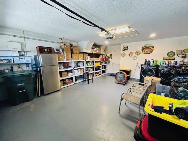 garage with washer and clothes dryer, a garage door opener, and stainless steel fridge