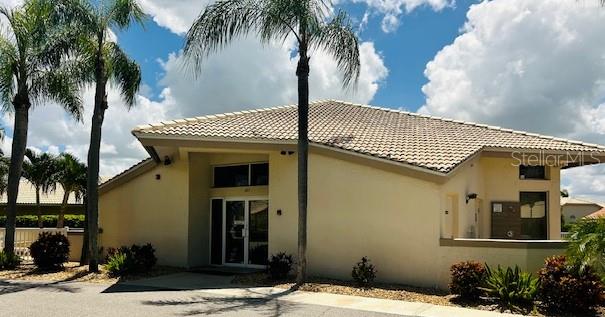 rear view of house featuring a tiled roof and stucco siding