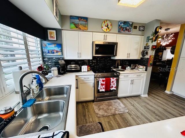 kitchen with white cabinetry, appliances with stainless steel finishes, light hardwood / wood-style floors, and sink