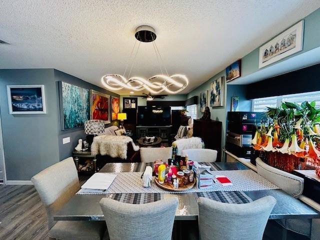 dining space featuring an inviting chandelier, wood-type flooring, and a textured ceiling