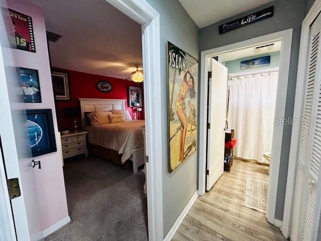 hall featuring light wood-style floors, visible vents, and baseboards