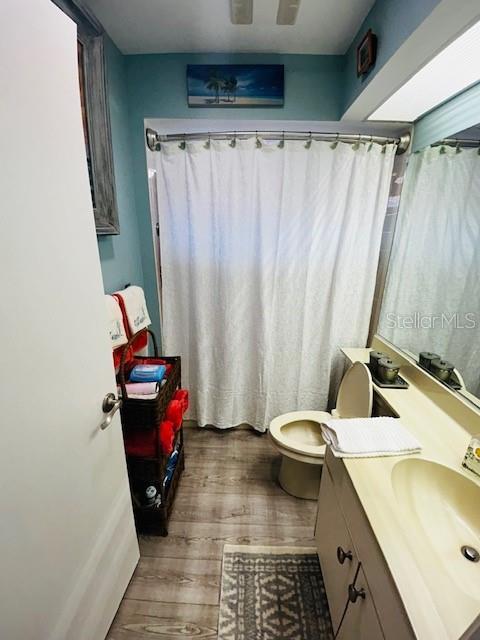 bathroom with toilet, wood finished floors, and vanity