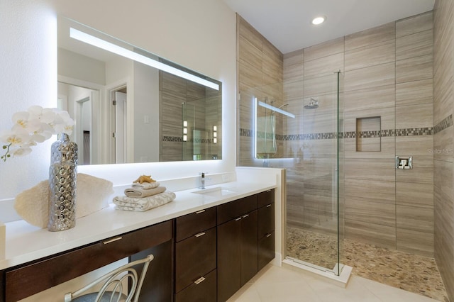 bathroom with tile patterned flooring, vanity, and tiled shower