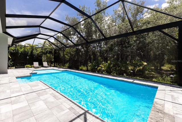 view of pool featuring glass enclosure and a patio