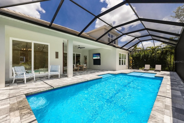 view of swimming pool with a patio, glass enclosure, and ceiling fan