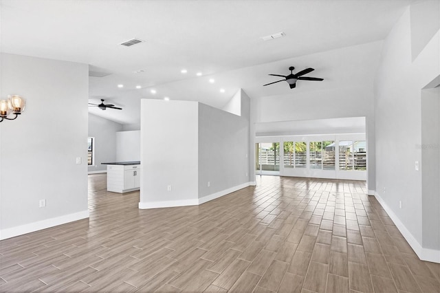 unfurnished living room featuring wood finish floors, visible vents, baseboards, and ceiling fan with notable chandelier