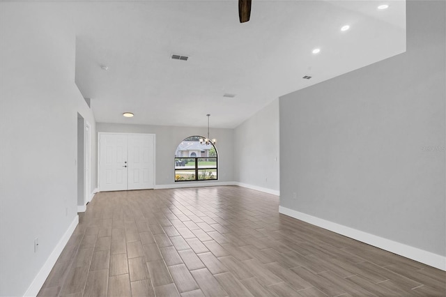 unfurnished living room with a chandelier, visible vents, light wood-style floors, and baseboards