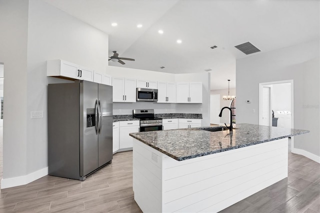 kitchen with a sink, visible vents, white cabinets, appliances with stainless steel finishes, and a center island with sink