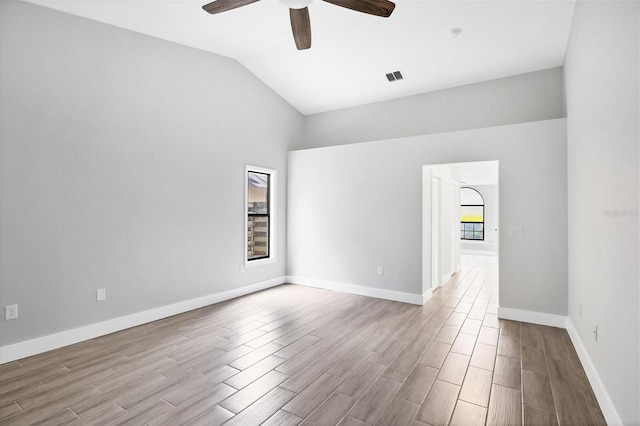 spare room featuring a ceiling fan, wood finish floors, visible vents, and vaulted ceiling