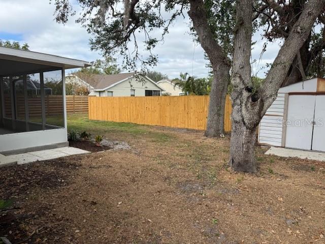 view of yard with a storage shed, fence, and a sunroom