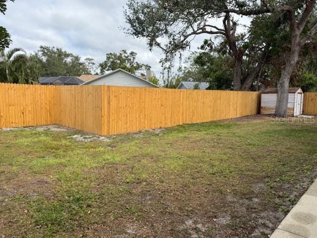 view of yard with a storage shed, a fenced backyard, and an outbuilding