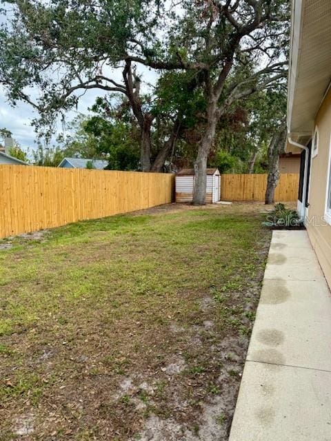 view of yard featuring a fenced backyard, a storage unit, and an outbuilding