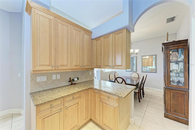 kitchen featuring kitchen peninsula, light stone counters, and light tile patterned flooring