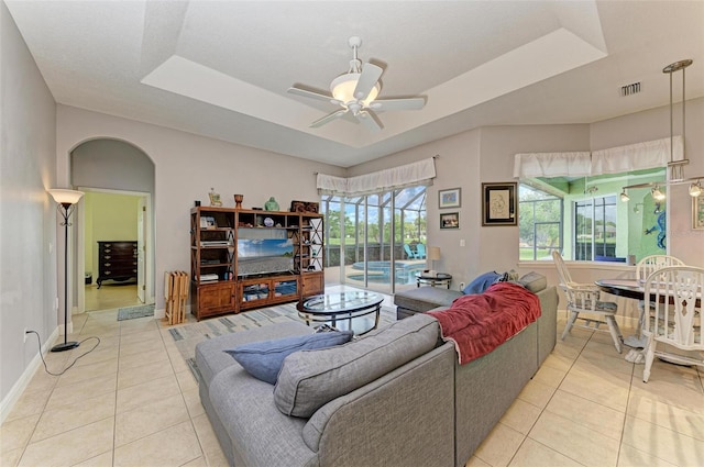 tiled living room featuring a tray ceiling and ceiling fan