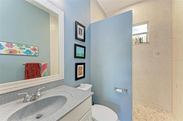 bathroom with tiled shower, vanity, and toilet