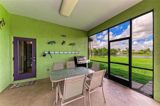 sunroom featuring ceiling fan and a water view