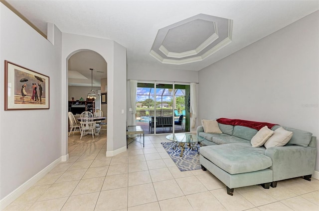 tiled living room featuring a tray ceiling and crown molding