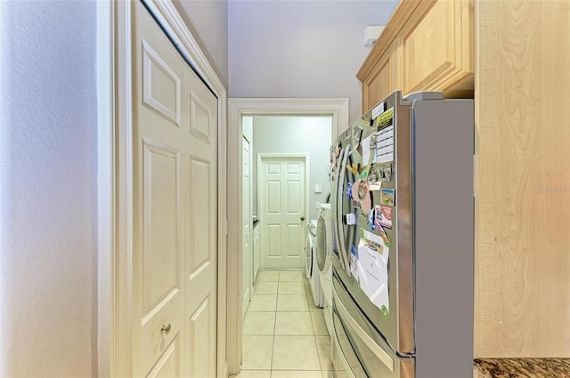 kitchen featuring washing machine and clothes dryer, stainless steel refrigerator, light brown cabinetry, and light tile patterned flooring