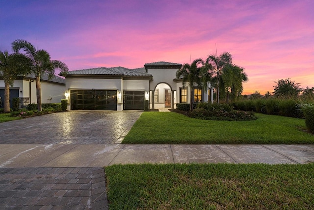 mediterranean / spanish home featuring a yard and a garage