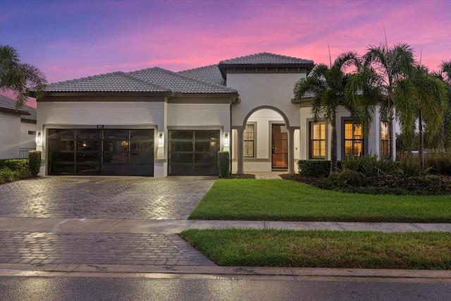 mediterranean / spanish home with a garage and a lawn