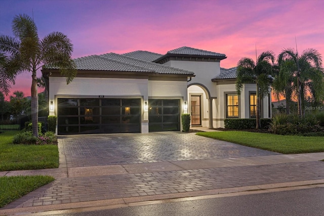 mediterranean / spanish-style house with a lawn and a garage