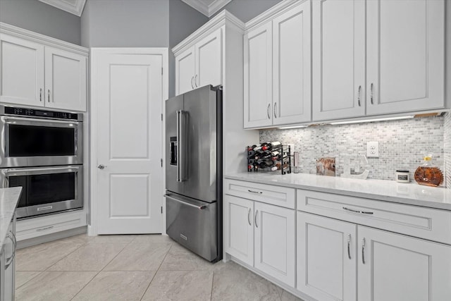 kitchen featuring stainless steel appliances, white cabinetry, tasteful backsplash, and ornamental molding