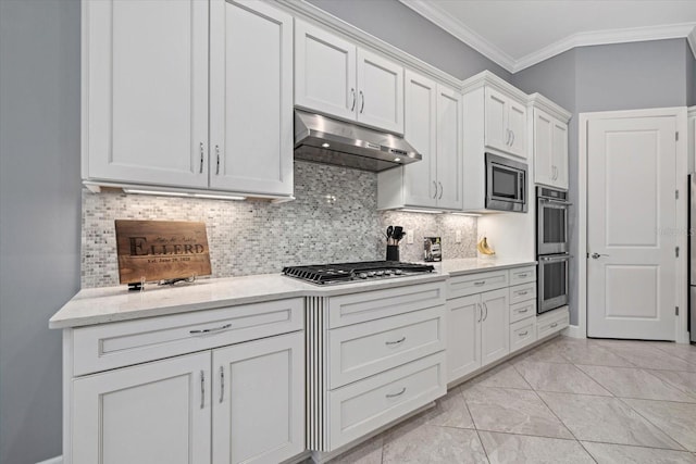 kitchen with white cabinets, light stone countertops, ornamental molding, appliances with stainless steel finishes, and tasteful backsplash