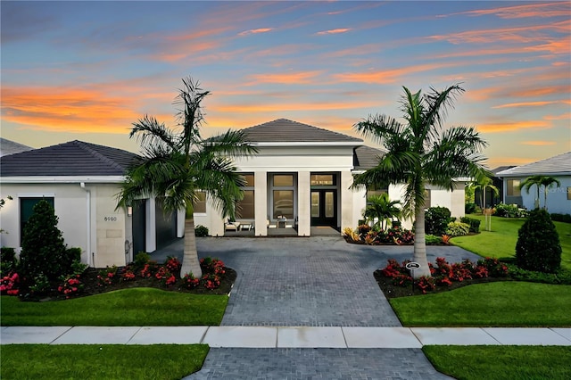 view of front of home featuring a lawn, decorative driveway, and stucco siding